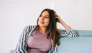 hopeful young hispanic woman sitting on a couch